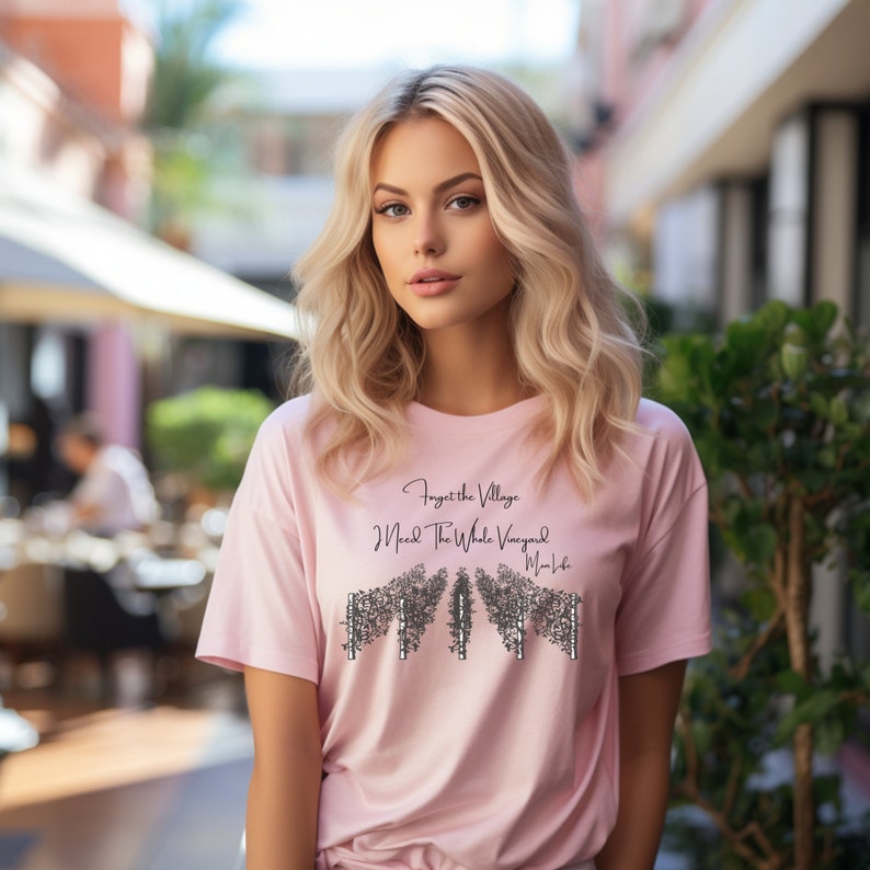 May include: A pink t-shirt with a black graphic that says "Forget the Village I Need the Whole Vineyard My Life".