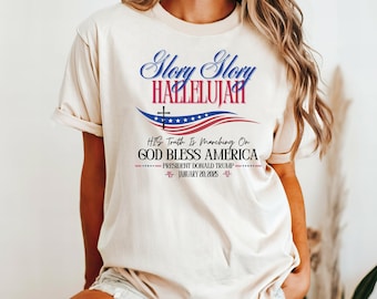 Könnte beinhalten: Ein weißes T-Shirt mit einem rot-weiß-blauen amerikanischen Flaggenmuster. Der Text "Glory Glory Hallelujah" ist in Blau über der Flagge gedruckt. Der Text "His Truth Is Marching On" ist in Blau unter der Flagge gedruckt. Der Text "God Bless America" ist in Blau unter der Flagge gedruckt. Der Text "President Donald Trump" ist in Blau unter der Flagge gedruckt. Der Text "January 20, 2025" ist in Blau unter der Flagge gedruckt.