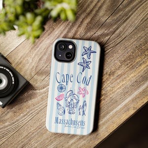 May include: A blue and white striped phone case with a design featuring a lobster, seashells, starfish, and the text "Cape Cod Massachusetts Nautical Club Est. 1950".