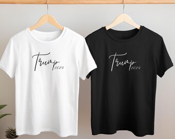 Könnte beinhalten: Zwei T-Shirts, eines weiß und eines schwarz, mit dem Text "Trump 2024" in handschriftlicher Schrift.