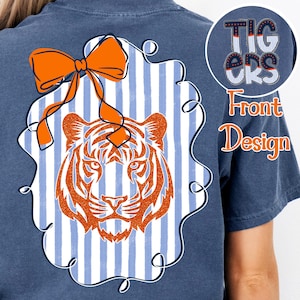 Op de afbeelding: Marineblauw T-shirt met een tijgerafbeelding. Het ontwerp heeft een oranje tijgerkop met strepen, een strik en een gestreepte achtergrond. De tekst "Tigers" staat rechtsboven. Het shirt heeft een ontwerp aan de voorkant.
