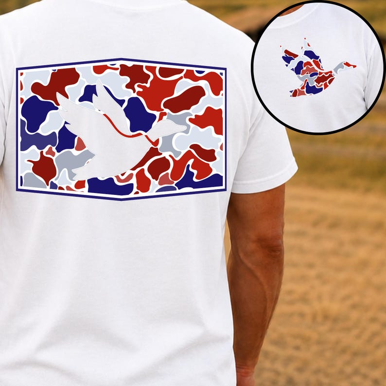 K&ouml;nnte beinhalten: Wei&szlig;es T-Shirt mit einer Grafik einer fliegenden Ente. Die Ente ist wei&szlig;, vor einem Tarnmuster aus roten, blauen und grauen Formen in einem blau umrandeten Rechteck. Eine kleinere Version der Entengrafik befindet sich oben rechts.