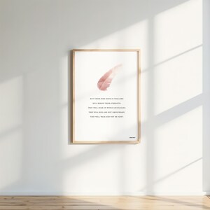 Op de afbeelding: Een ingelijste print met een licht houten frame en een witte achtergrond. De print toont een roze veergrafiek en zwarte tekst. De tekst luidt: "Maar wie op de Heer hopen, putten nieuwe kracht."