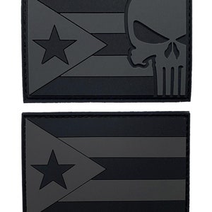 Puede incluir: Dos parches bordados en negro y gris. El parche superior presenta la bandera de Puerto Rico con un gráfico de calavera y huesos cruzados. El parche inferior presenta la bandera de Puerto Rico.