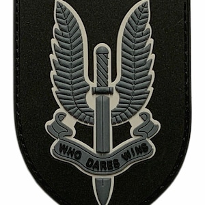May include: A black and gray embroidered patch with a winged dagger and the text "Who Dares Wins".