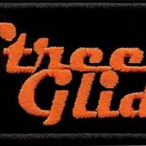 Könnte beinhalten: Orangefarbener gestickter "Street Glide"-Aufnäher auf schwarzem Hintergrund.