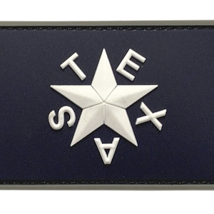 Op de afbeelding: Een blauwe en witte geborduurde patch met het woord "TEXAS" gespeld rond een witte vijfpuntige ster.