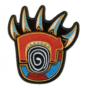 May include: A colorful embroidered patch depicting a bear paw print with a spiral design inside. The paw print is outlined in black and features blue, red, white, and yellow accents.