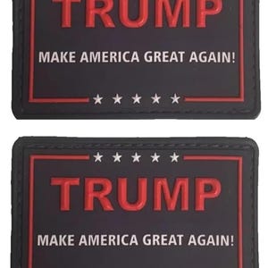 以下が含まれることがあります： 「TRUMP MAKE AMERICA GREAT AGAIN!」という白い文字が書かれた、黒と赤の刺繍パッチが2つ。パッチは赤い縁取りがされており、文字の上下には白い星が並んでいます。