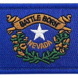 May include: Embroidered patch featuring the state flag of Nevada. The patch is blue with a gold star and the words "Battle Born" and "Nevada" in gold. The star is surrounded by two gold wreaths of green leaves.