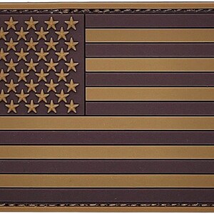 May include: A brown and tan American flag patch with a stitched border. The flag is made of a textured material.