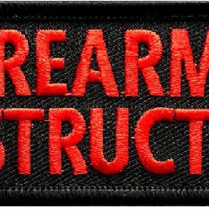 May include: Black patch with red embroidered text that reads "FIREARMS INSTRUCTOR"
