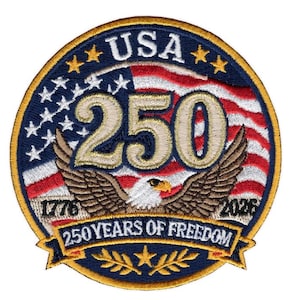 May include: A circular embroidered patch featuring a bald eagle with wings spread over a background of the American flag. The text USA, 250, 1776, 2026, and 250 YEARS OF FREEDOM are stitched in gold and white. The border is gold with a dark blue edge.