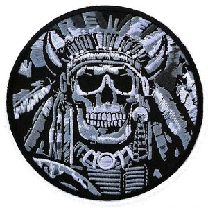 May include: A black and white embroidered patch of a skull wearing a Native American headdress. The skull is surrounded by feathers and the headdress has a beaded design.