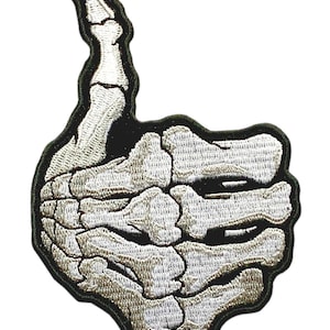 May include: A white skeleton hand giving a thumbs up gesture. The hand is embroidered on a black patch.