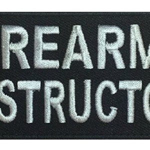 Könnte beinhalten: Schwarzer rechteckiger Aufnäher mit dem in weißem Faden gestickten Schriftzug "FIREARMS INSTRUCTOR". Der Text ist in einer fetten, serifenlosen Schriftart gehalten, und der Aufnäher hat einen schwarzen Rand.
