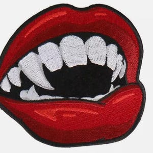 Pode incluir: Patch bordado com lábios vermelhos e presas brancas afiadas, com interior preto. O patch apresenta um design detalhado, ideal para personalizar roupas ou acessórios com um toque único.