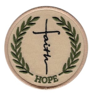 May include: A circular embroidered patch with a beige background and a tan border. The design features a black cross integrated with the word faith written vertically in script, flanked by two green olive branches and the word HOPE in green.