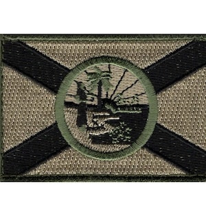 May include: A green, black, and tan embroidered patch featuring the state flag of Florida. The flag has a white cross on a red field with a green circle in the center containing a depiction of a tree and a seal.
