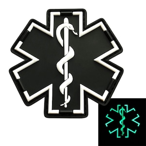 May include: Black and white star of life patch with a white snake and staff symbol in the center. The patch glows green in the dark.