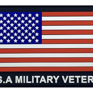 Puede incluir: Un parche rectangular con el diseño de la bandera estadounidense, con rayas rojas y blancas y un campo azul con estrellas blancas. El texto "U.S.A MILITARY VETERAN" está en blanco sobre fondo negro.