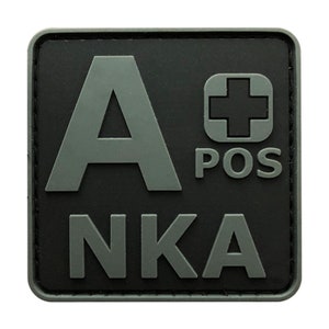 May include: A black and grey square patch with the letters "A POS" and the word "NKA" in grey. A red cross is in the top right corner.