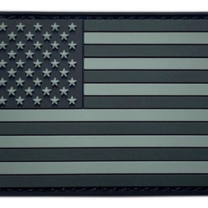 May include: A black and gray American flag patch with a textured surface. The flag is made of a durable material and is perfect for adding a patriotic touch to any item.