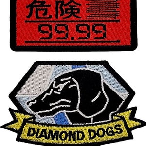 May include: Two embroidered patches. The first is red with black text that reads "ALERT 危険 99.99". The second is a diamond shape with a black dog head and a yellow banner that reads "DIAMOND DOGS".