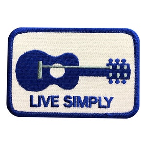 May include: Blue embroidered patch with a white background. The patch features a blue guitar with a gray fretboard and the text "LIVE SIMPLY".