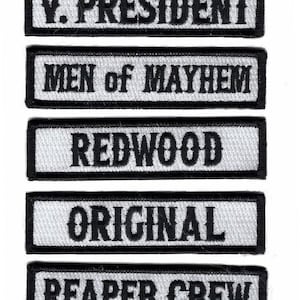 Peut inclure: Cinq patchs brodés blancs et noirs avec le texte suivant : "V. PRESIDENT", "MEN of MAYHEM", "REDWOOD", "ORIGINAL", et "REAPER CREW".