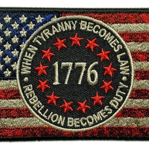 以下が含まれることがあります： アメリカの旗のデザインが刺繍されたパッチ。パッチの中央には、円の中に「When Tyranny Becomes Law, Rebellion Becomes Duty」というテキストと「1776」という年号が星で囲まれています。