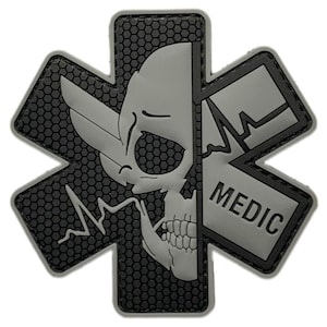 May include: A grey and black embroidered patch with a skull and crossbones design. The crossbones are in the shape of a medical star of life. The text "MEDIC" is on the patch.