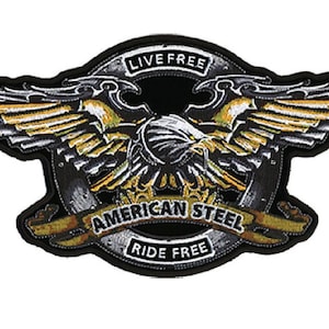 Op de afbeelding: Geborduurde patch met een gedetailleerde adelaar met uitgespreide vleugels, in tinten goud, zwart en wit. De patch bevat de tekst "LIVE FREE" bovenaan en "AMERICAN STEEL RIDE FREE" onderaan, met een zwarte rand.