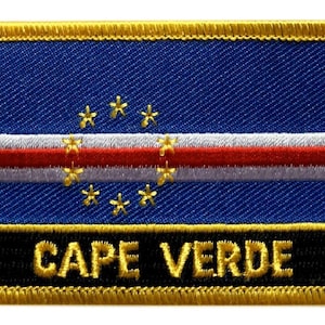 Puede incluir: Un parche bordado en oro con la bandera de Cabo Verde. La bandera es azul con una franja horizontal blanca y roja y diez estrellas doradas.