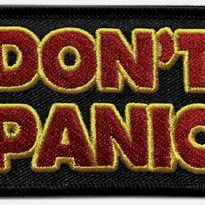 Puede incluir: Un parche bordado negro con las palabras "DON'T PANIC" en rojo con un contorno amarillo.