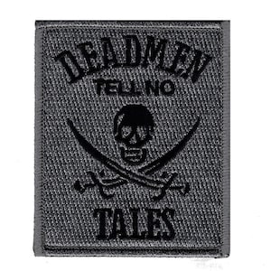 Puede incluir: Parche bordado en negro y gris con una calavera y huesos cruzados, el texto "Dead Men Tell No Tales" y un fondo gris.