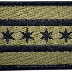 May include: A green and black embroidered patch featuring the Chicago flag. The flag has four white six-pointed stars on a white field, with two black horizontal stripes above and below the stars.