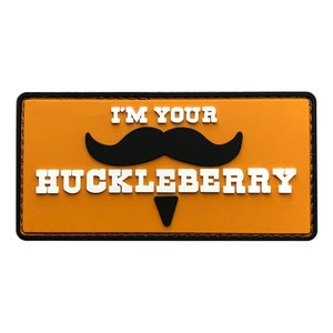 May include: Orange patch with black stitching around the edges. The patch has white text that reads "I'm your Huckleberry" with a black mustache and a small black goatee.