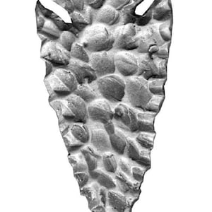 Puede incluir: Una punta de flecha gris hecha de piedra con una superficie rugosa y texturizada.