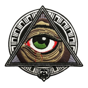 May include: An embroidered patch featuring a large eye inside a triangle, surrounded by a circle with a geometric pattern. The eye is green with a red tear, and the triangle is outlined in black. The patch is perfect for adding a unique touch to clothing, bags, or other accessories.