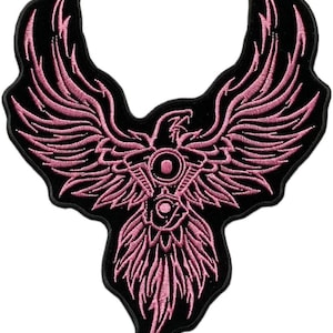 May include: Embroidered patch featuring a pink phoenix design on a black background. The phoenix has outstretched wings and intricate detailing. The patch is likely for clothing or accessories.