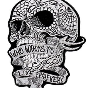 May include: Black and white embroidered patch of a sugar skull with intricate details. The skull is wearing a banner that reads "Who wants to live forever?"