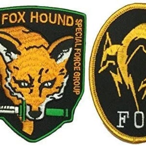 May include: Two embroidered patches, one featuring a fox head with a knife and the text "FOX HOUND SPECIAL FORCE GROUP", the other featuring a stylized fox with the text "FOX".