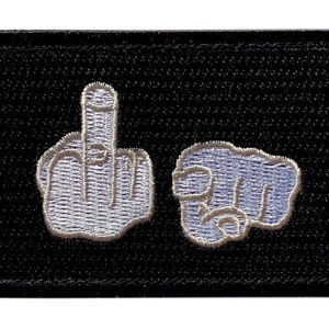 May include: Black embroidered patch with two white hands, one giving the middle finger and the other pointing forward.