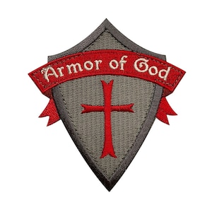 May include: A gray embroidered patch shaped like a shield with a red cross in the center and a red banner with the text "Armor of God" in white.