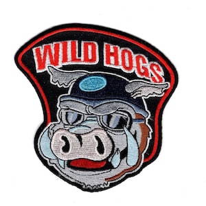 Könnte beinhalten: Gestickter Aufnäher mit einem Cartoon-Schwein, das einen Helm und eine Schutzbrille trägt. Das Schwein lächelt und hat einen roten Mund. Der Text "WILD HOGS" befindet sich über dem Schwein in weißen Buchstaben mit rotem Rand.