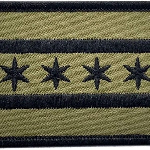 May include: A green and black embroidered patch featuring the Chicago flag. The flag has six white stars on a white stripe, with two black stripes above and below the white stripe.