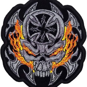 Peut inclure: Patch brodé thermocollant représentant un crâne avec des flammes et une croix dans un cercle. Le crâne est gris, les flammes sont orange et jaunes, et la croix est grise.