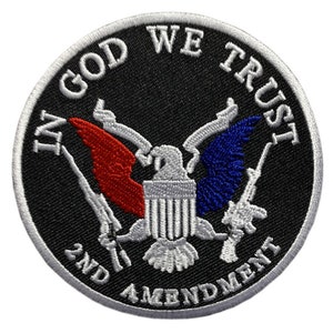 以下が含まれることがあります： 黒と白の刺繍パッチで、ハクトウワシがそれぞれのつめでライフルを持っている。ワシは黒い背景の中心にあり、縁には白い円がある。「In God We Trust」という文字がワシの周りを囲む白い円に書かれている。「2nd Amendment」という文字がワシの下の白い円に書かれている。