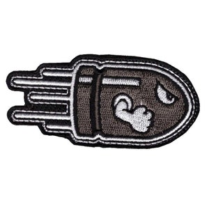May include: A black and white embroidered patch of a cartoon bullet with a frowning face and a clenched fist.